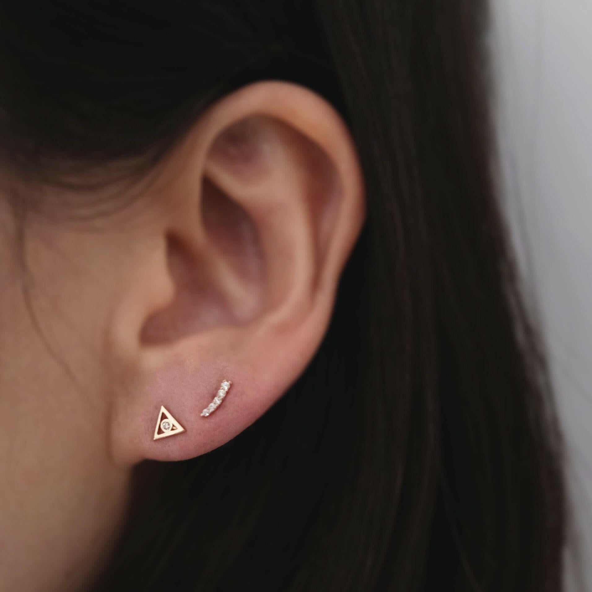 Geometric studs combined with dainty gold earrings for curated stack