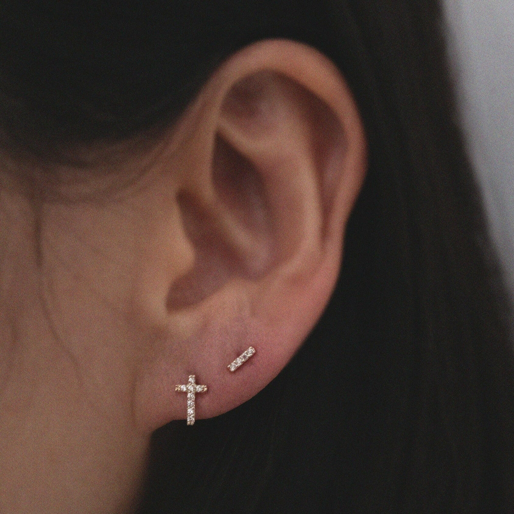 10K gold cross earrings paired with little bar shaped studs for a layered faith-inspired look