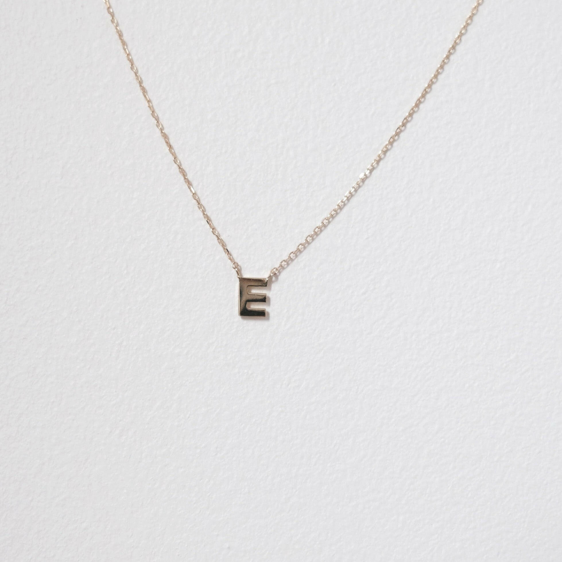 Macro image of 10K solid gold initial necklace with letter E pendant, minimal and shiny