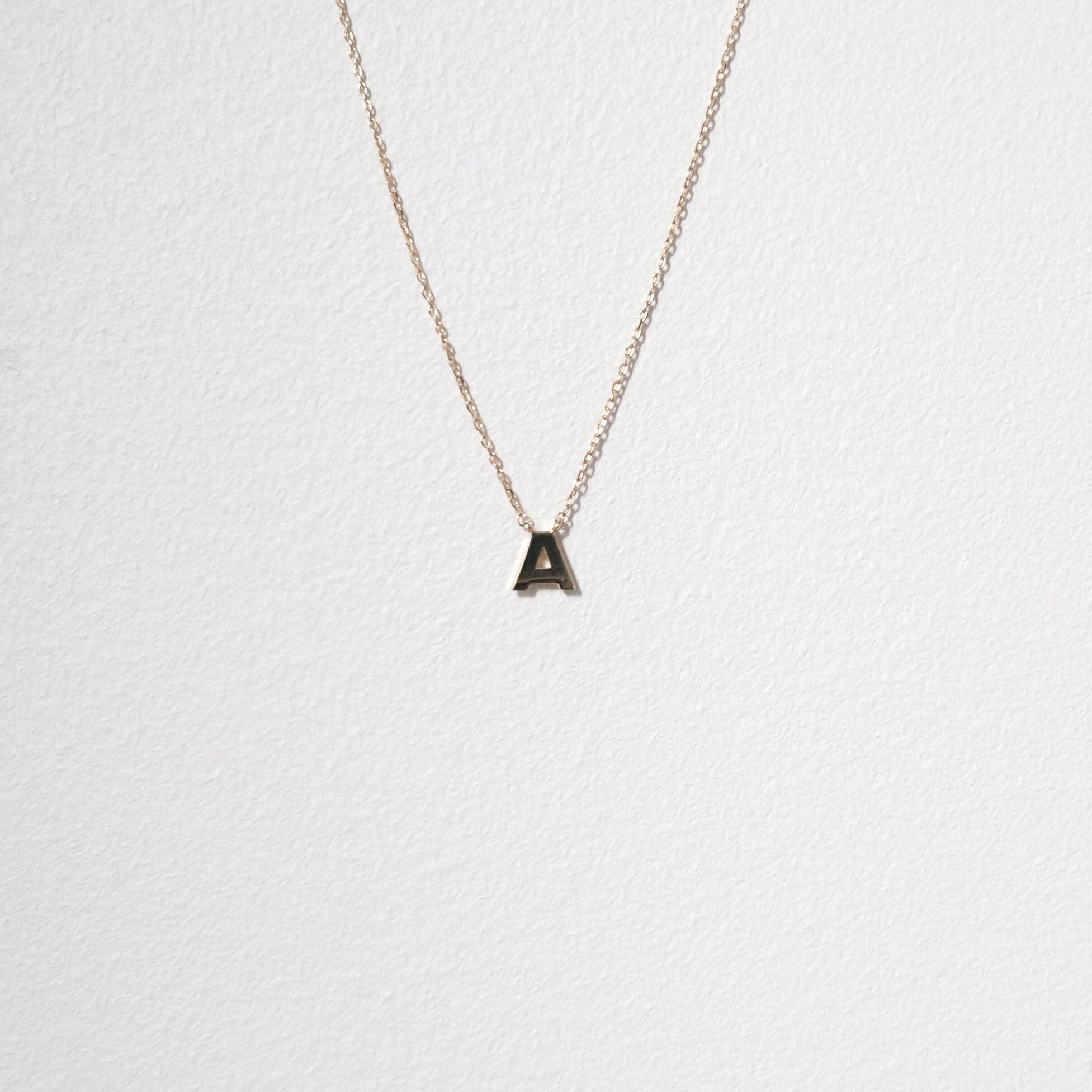 Close-up of 10K gold initial necklace featuring the letter A, with high polish detail in focus