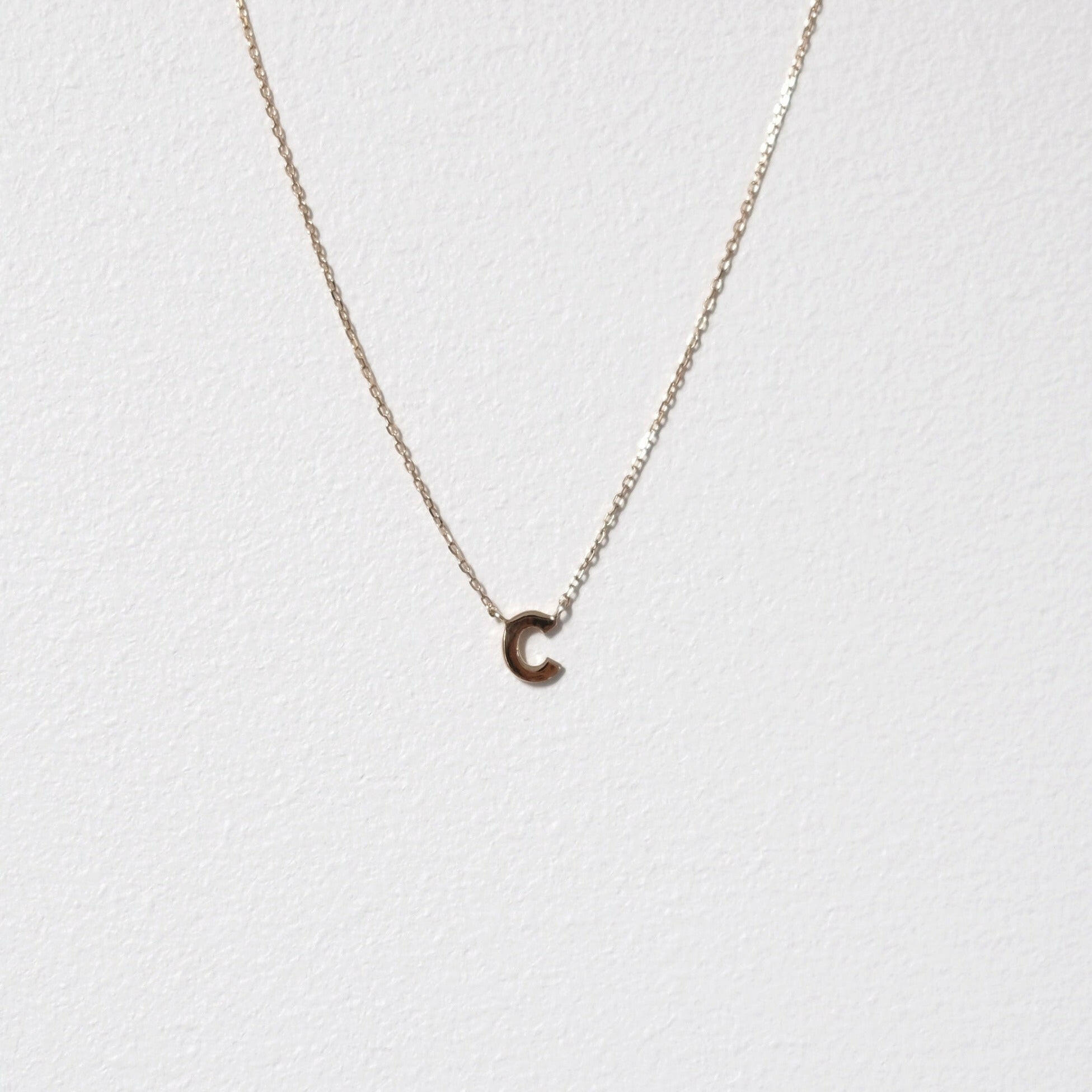 Detailed shot of 10K gold letter C pendant showcasing smooth serif edges on a white background