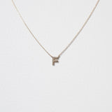Elegant close-up of 10K gold F pendant highlighting classic serif design and reflective polish