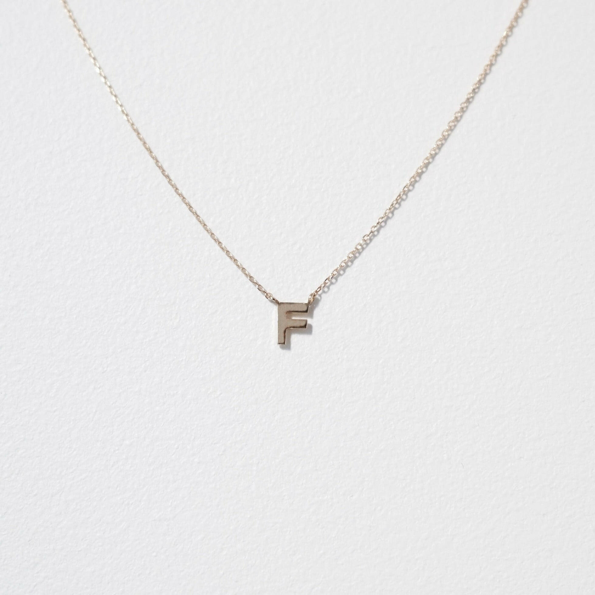 Elegant close-up of 10K gold F pendant highlighting classic serif design and reflective polish