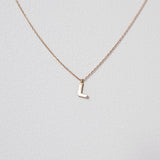 Refined close-up of the letter L pendant in 10K solid gold, photographed with chain slightly out of focus