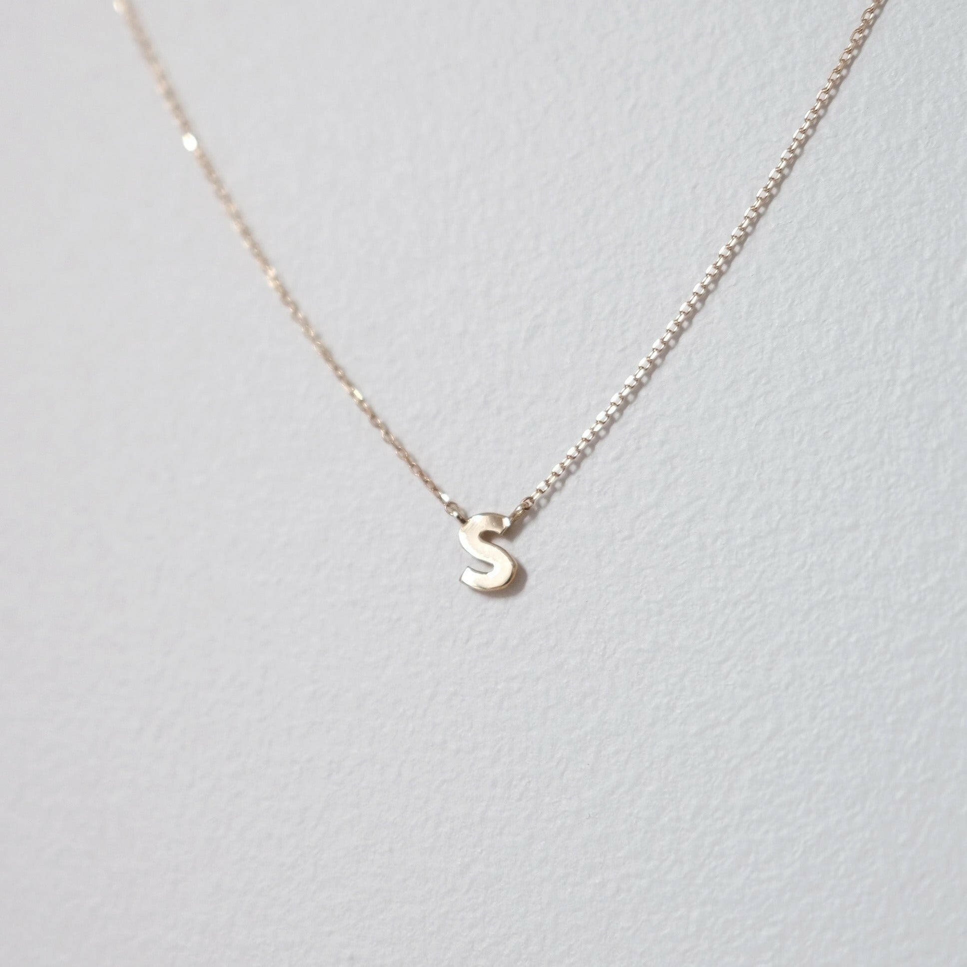 Stylish close-up of letter S initial in polished 10K gold, captured under soft light for clarity