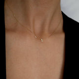 Model wearing the necklace with a minimalist black jacket, initial sitting perfectly above collarbone
