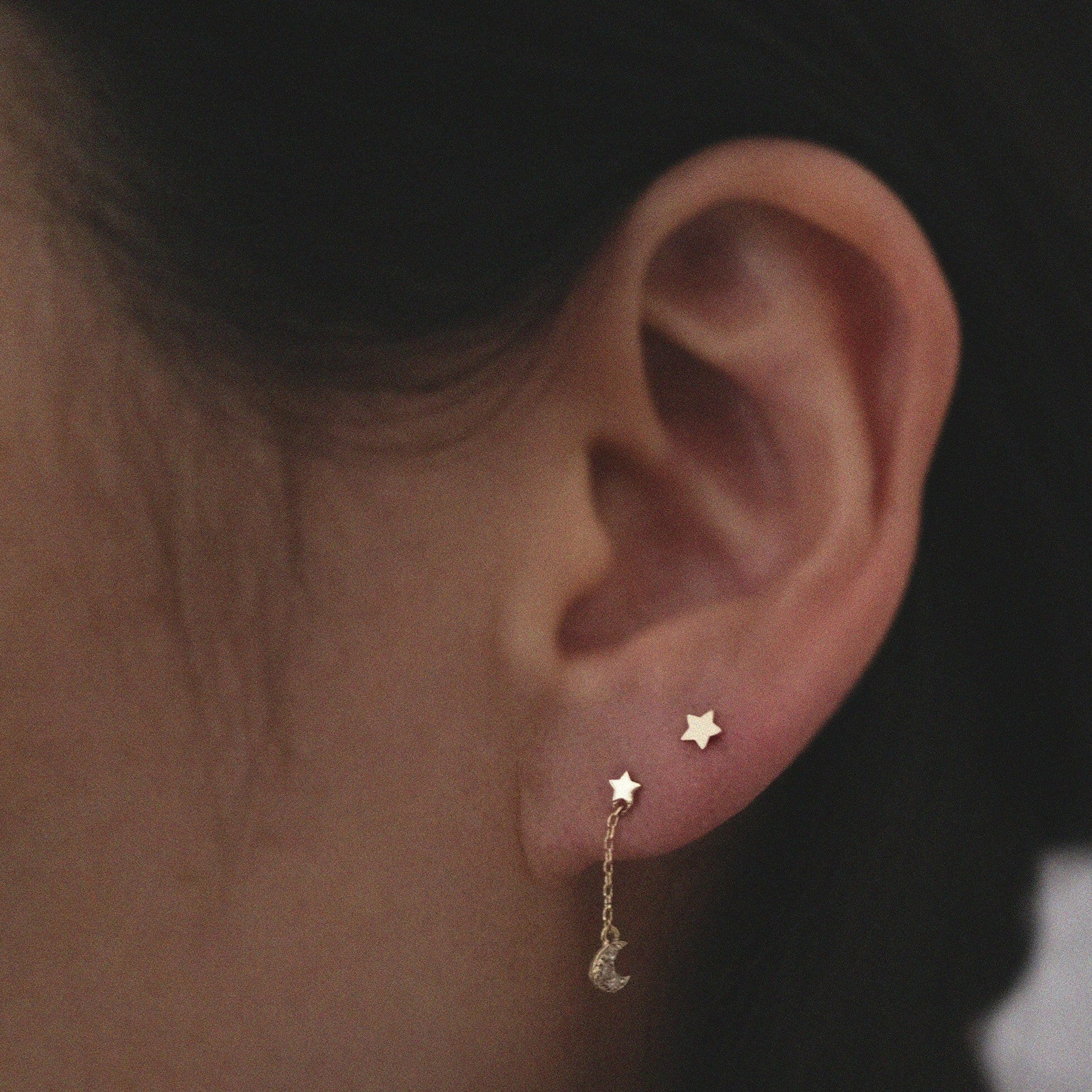 Model wearing Petite Star Studs in second piercing with celestial drop chain studs