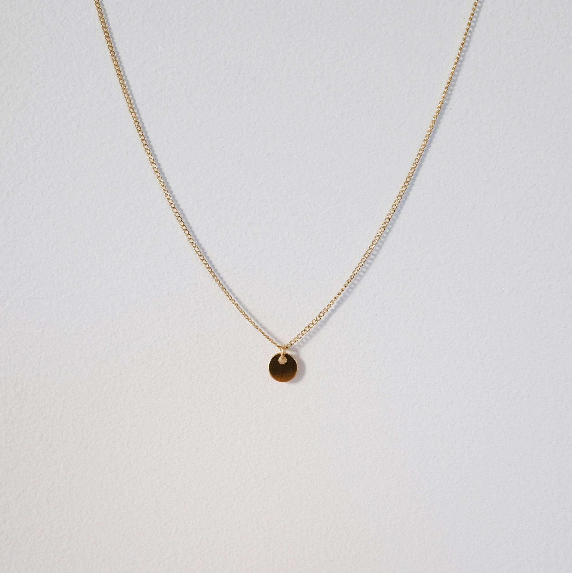 Close-up of circular disc pendant on fine chain