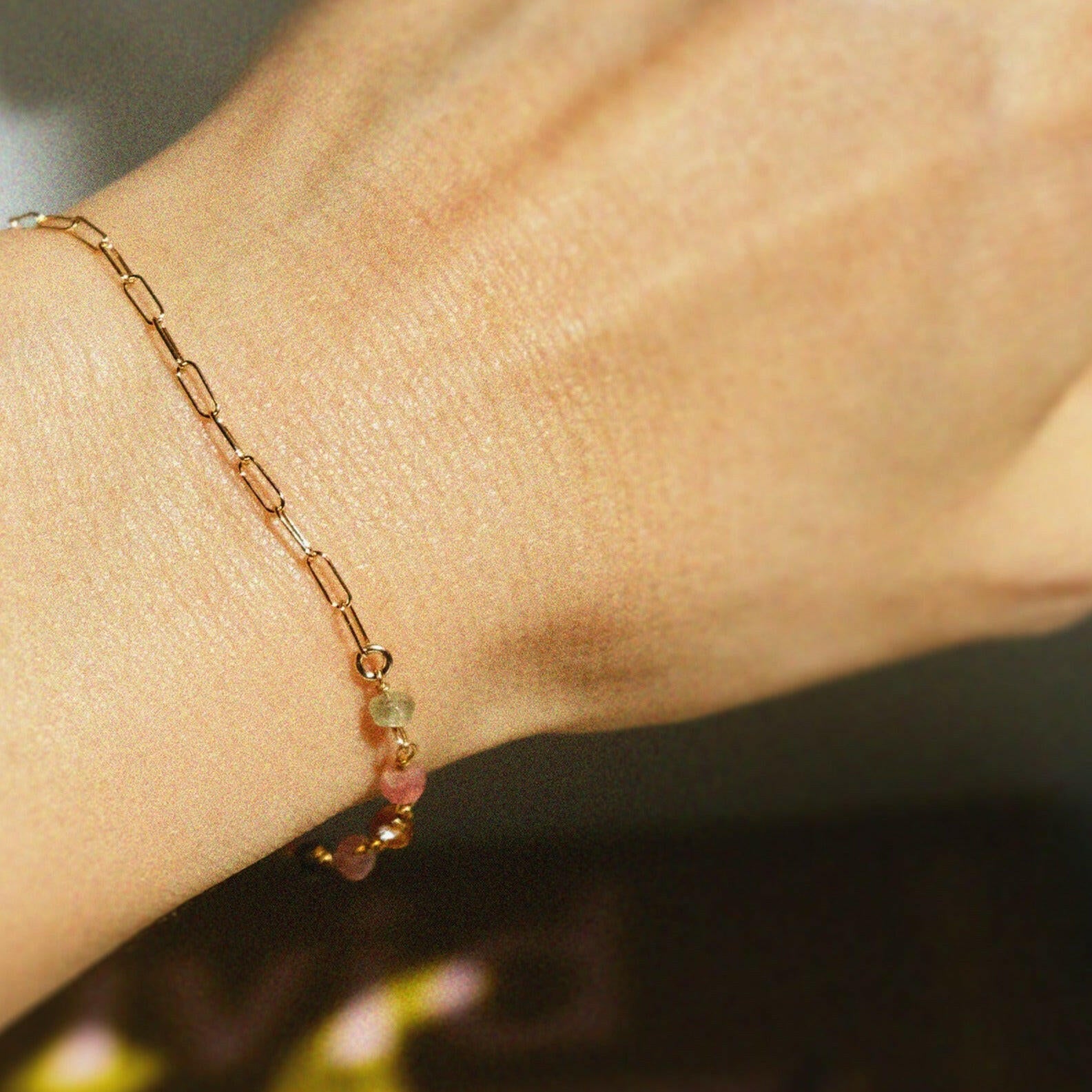 Dainty link and gemstone bracelet styled solo on wrist with bright natural light