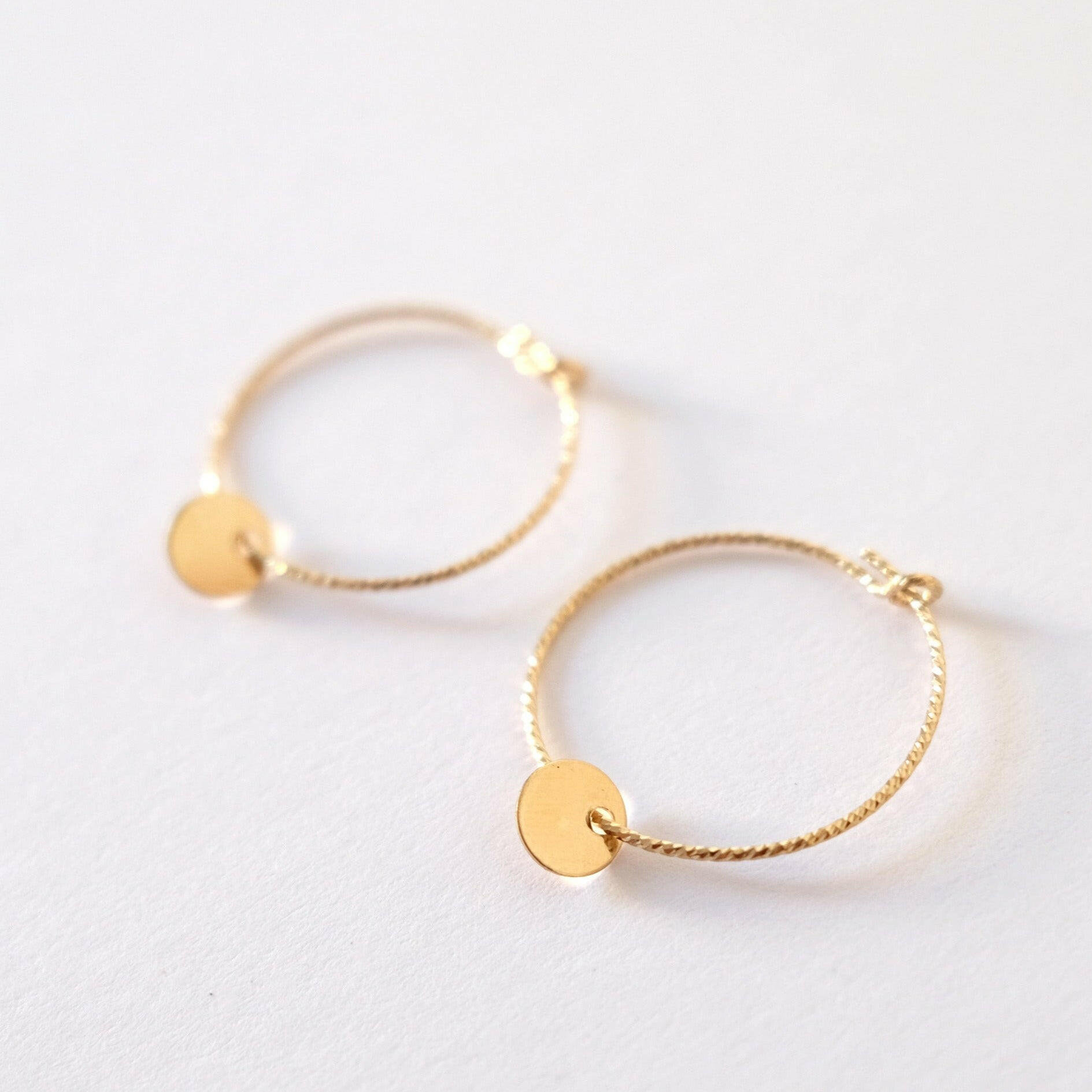 Close-up of the Aster Hoop earring highlighting the hanging gold disc