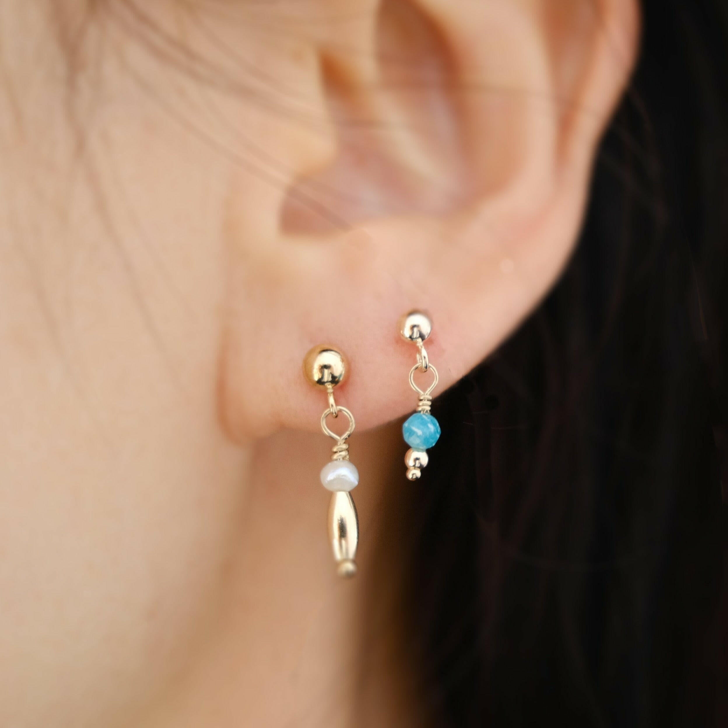 Model styling Carina pearl earrings with small dangly blue opal gemstone studs for a minimal stacked look