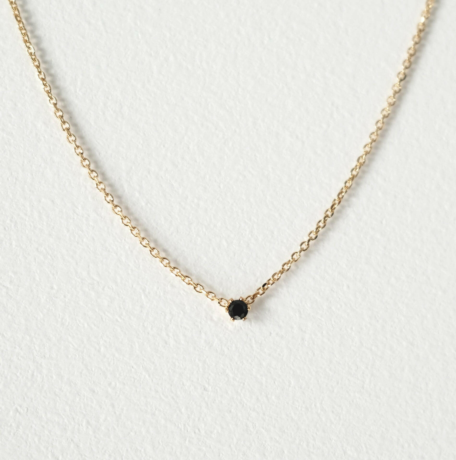 Elegant crystal necklace featuring black cubic zirconia and gemstone on a dainty chain with a petite pendant.