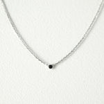 Elegant crystal necklace featuring black cubic zirconia and gemstone on a dainty chain with a petite pendant.