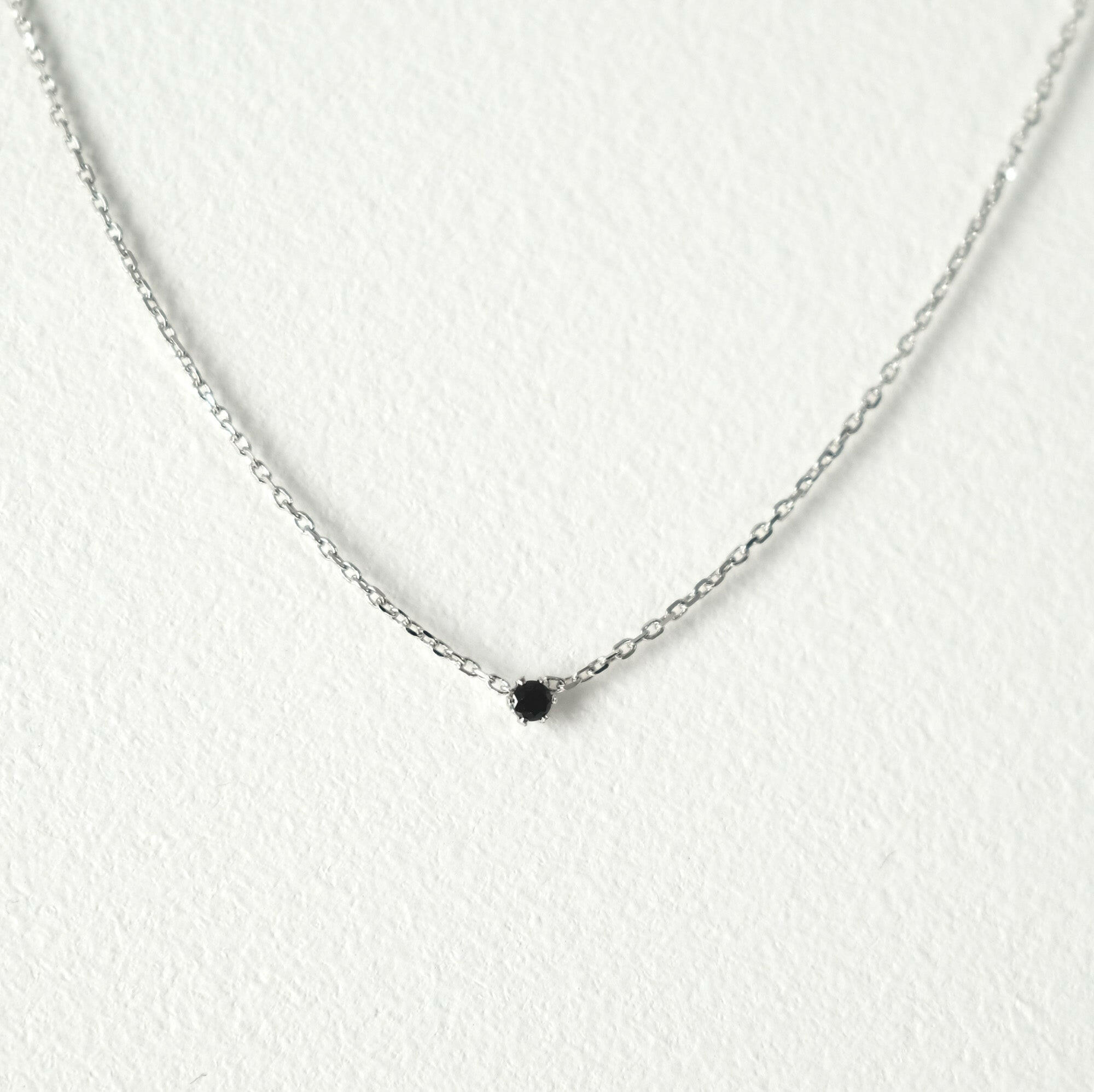 Elegant crystal necklace featuring black cubic zirconia and gemstone on a dainty chain with a petite pendant.