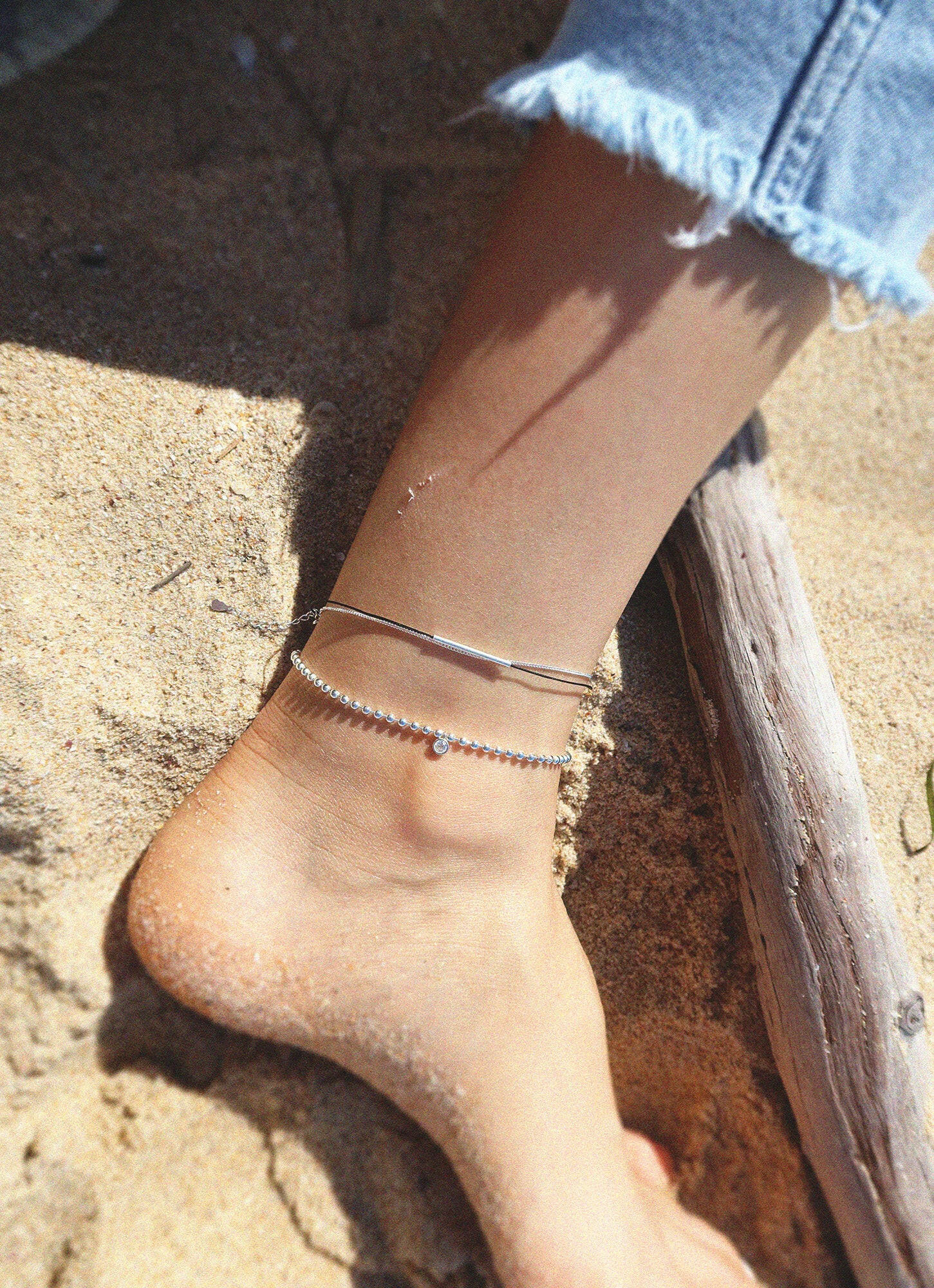 Elegant anklet featuring thread chain and silver bar accent, perfect jewelry piece for a stylish casual look.