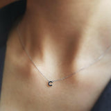 Necklace with a small letter 'T' pendant on a person's neck