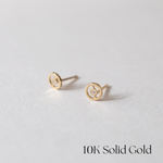 Angled view of circular gold earrings highlighting their shine and design