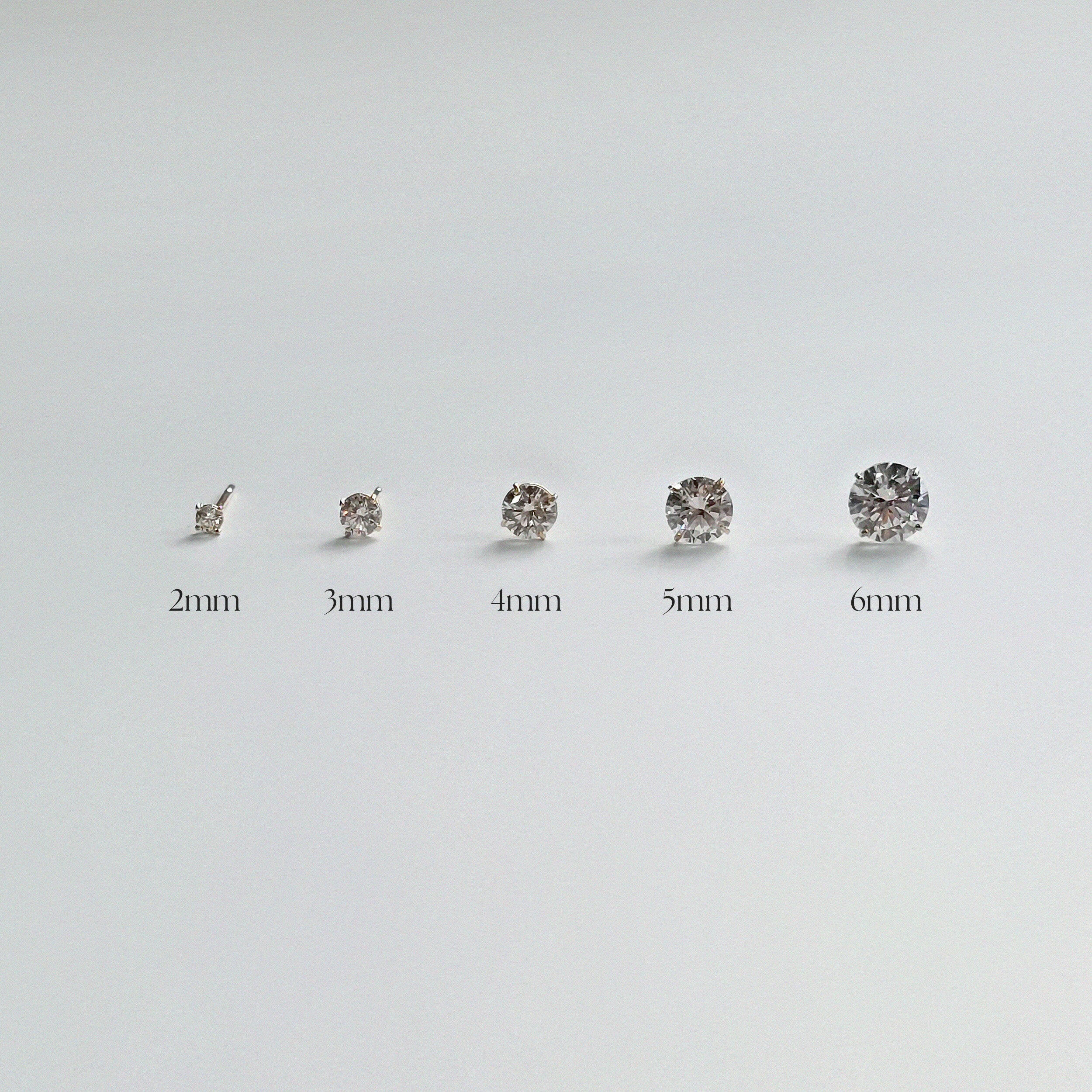 Five 14K gold crystal stud earrings displayed in ascending size order—2mm, 3mm, 4mm, 5mm, and 6mm—on a white background with labels beneath each earring for size reference