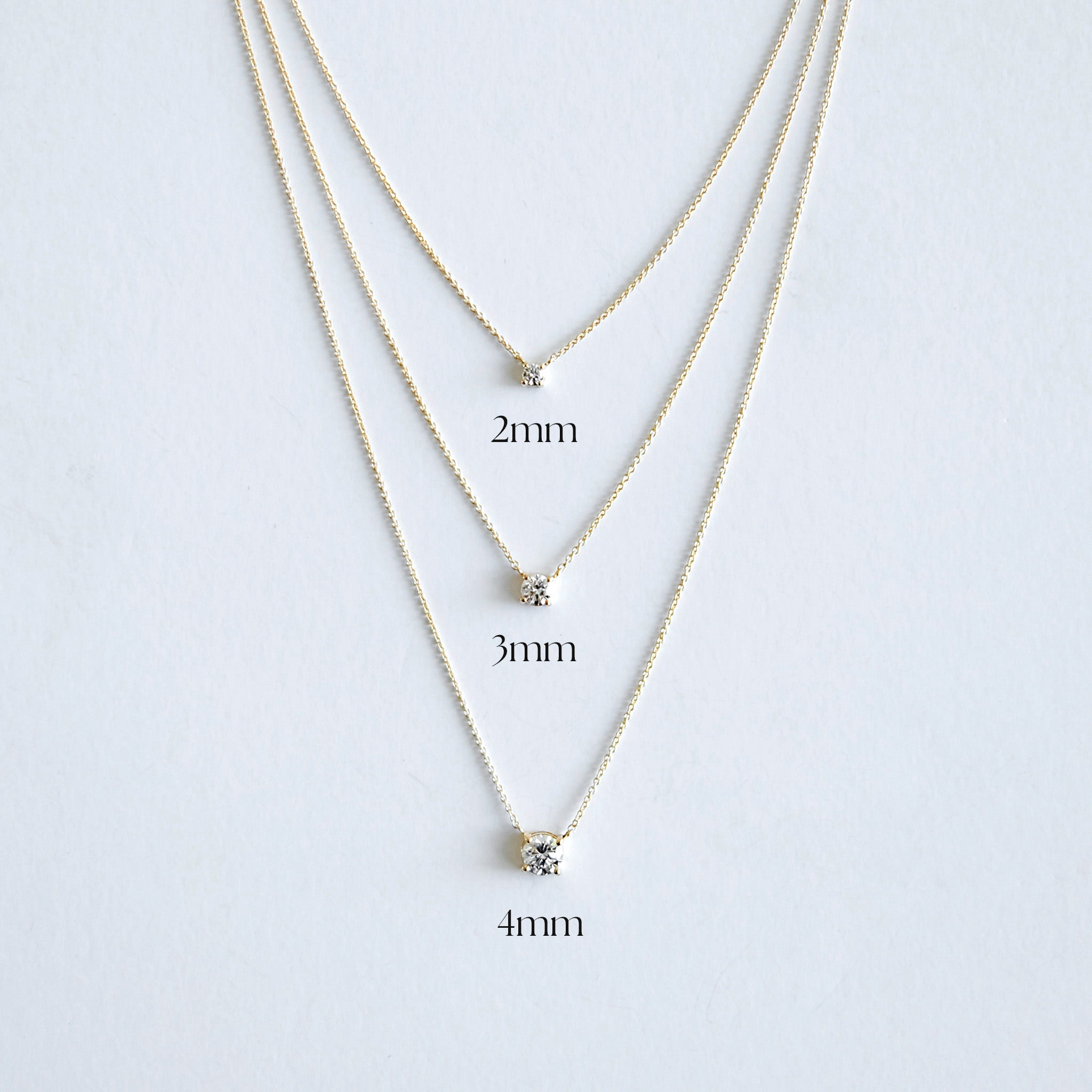 Three gold necklaces with varying diamond sizes on a white background