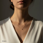 Close-up of a person wearing a delicate necklace with a plain background