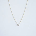 Delicate necklace with a small round pendant on a light gray background