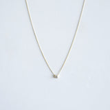 Delicate necklace with a small round pendant on a light gray background