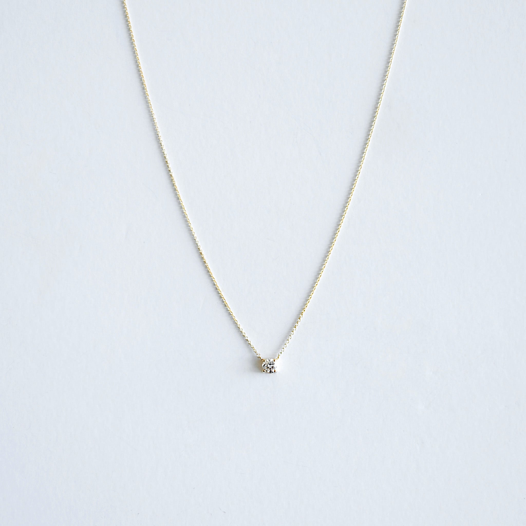 Delicate necklace with a small round pendant on a light gray background