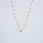 Gold necklace with a small pendant on a light gray background