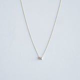 Gold necklace with a small pendant on a light gray background