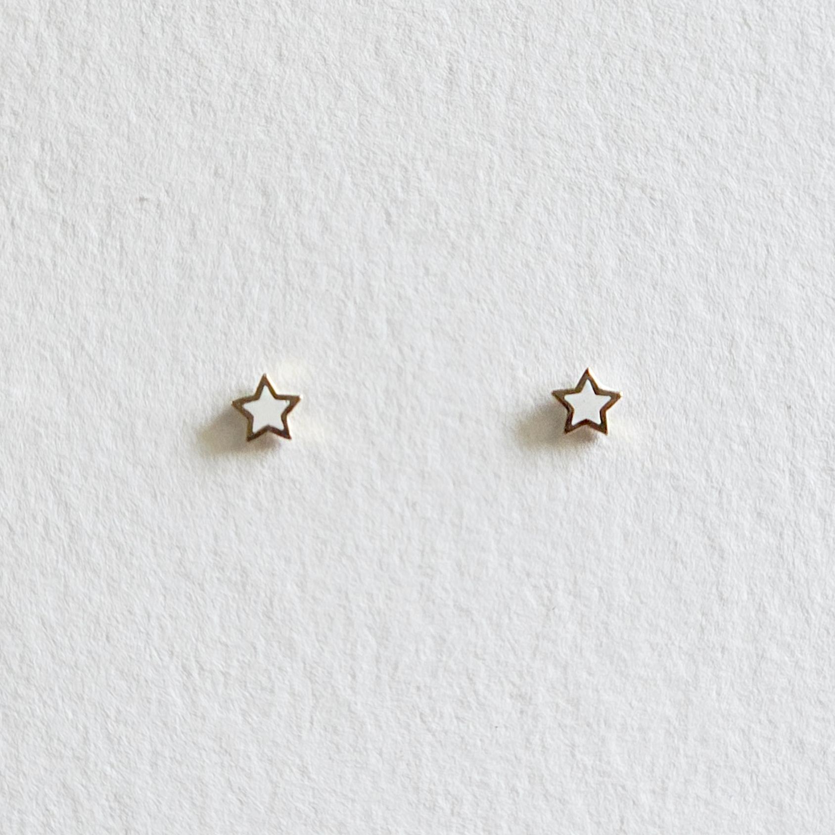 Minimalist gold star-shaped earrings photographed front-facing