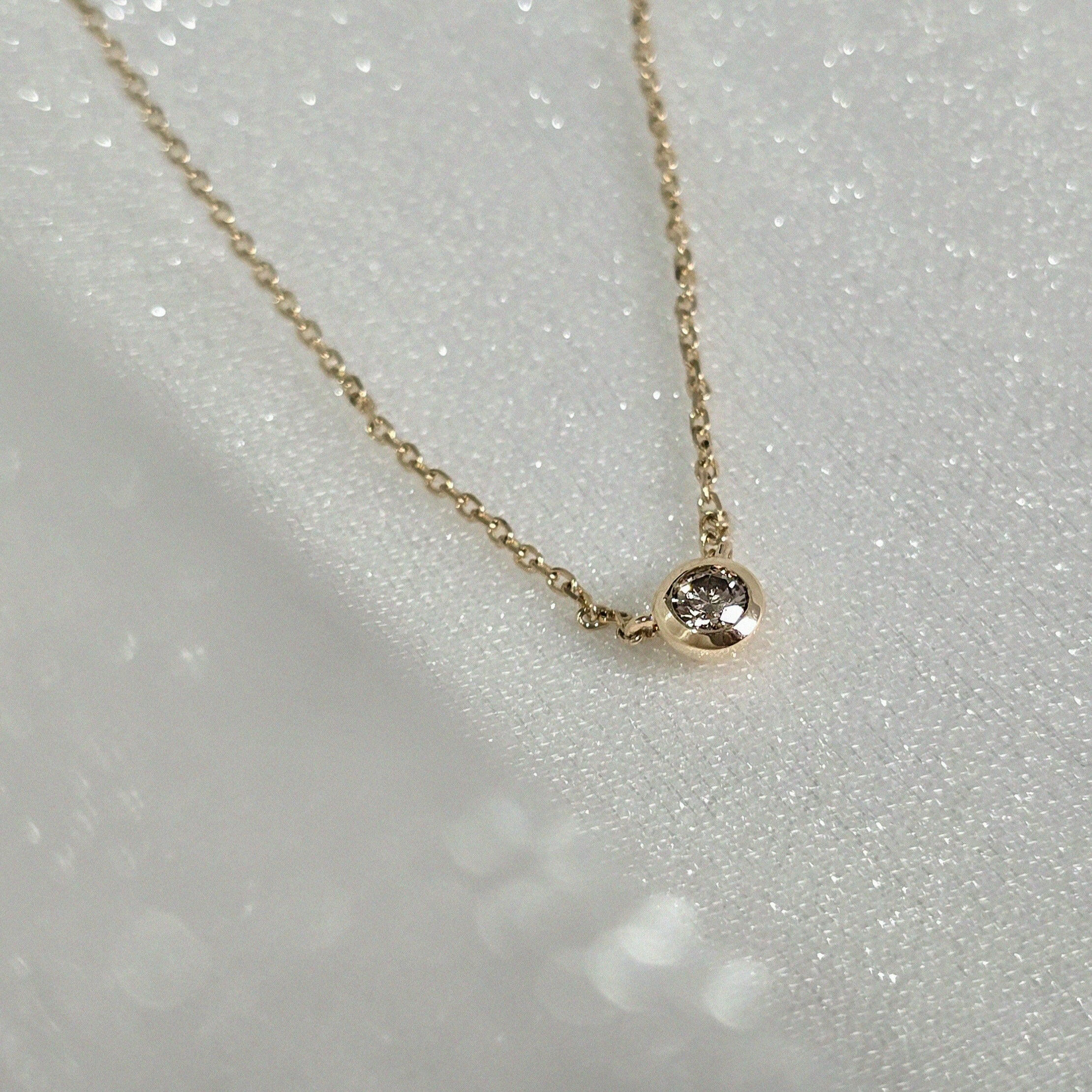 Angled shot of bezel pendant showing depth and polished edge – minimalist design in 14K gold