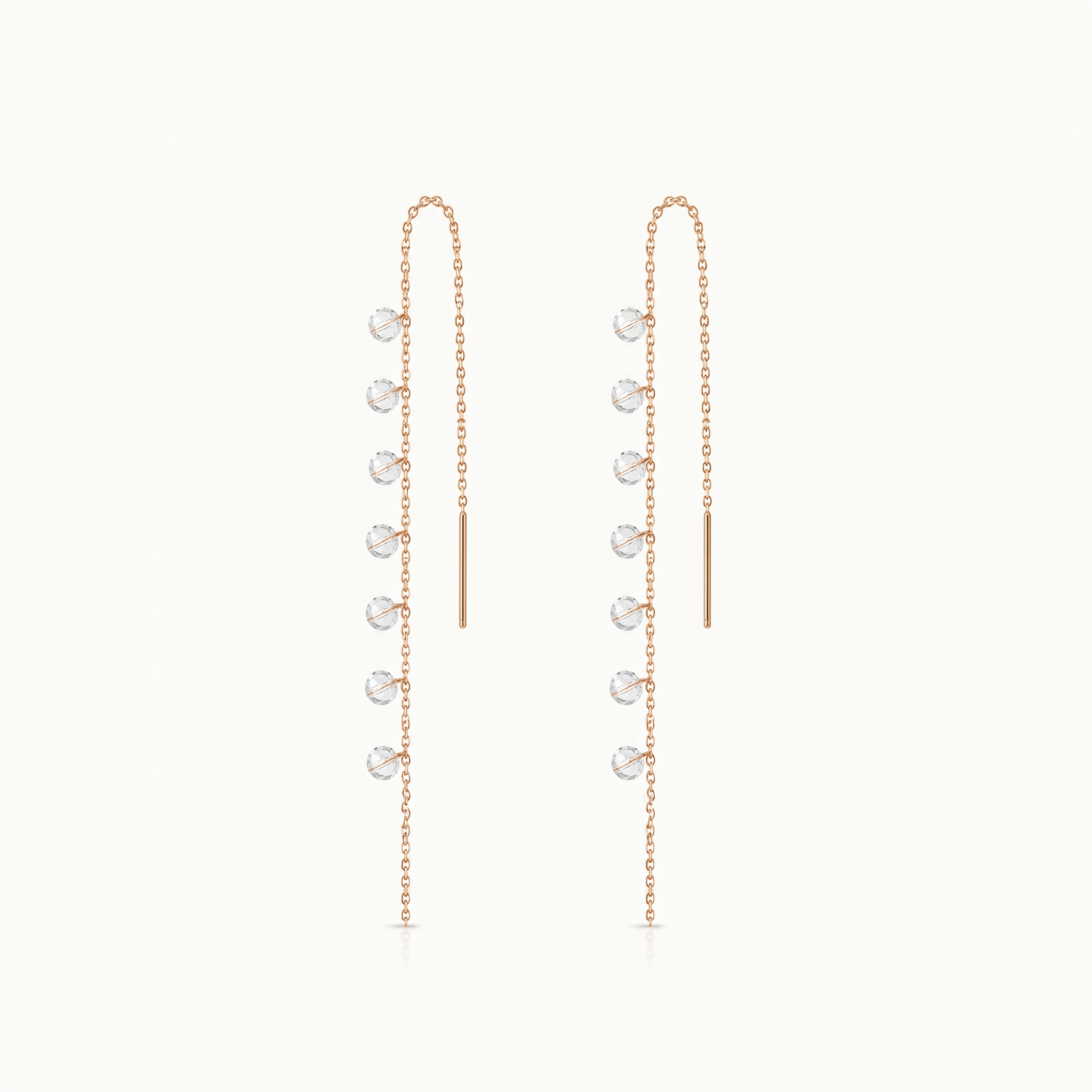 Pair of gold earrings with small round stones on a white background