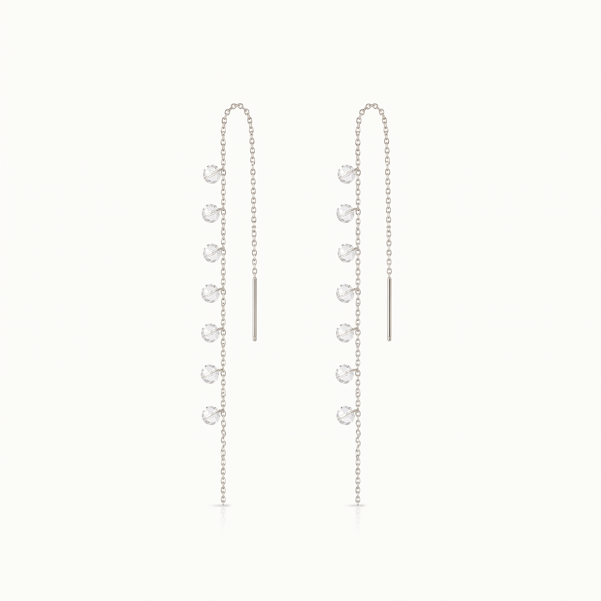 Pair of silver chain earrings with small round pendants on a white background