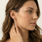 Close-up of a woman wearing a dangling earring with a neutral background