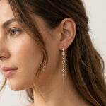 Close-up of a woman wearing elegant diamond threader earrings with a neutral background