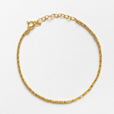 Gold chain bracelet on a light gray background