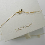 Gold bracelet on a white stand with 'LAONDRIM' branding.