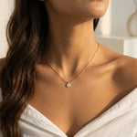 Close-up of a woman wearing a gold necklace with a small round pendant.