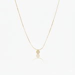 Gold necklace with  circular pendant on a white background