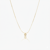 Gold necklace with  circular pendant on a white background