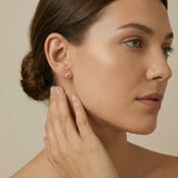 Woman wearing a delicate earring with a neutral background