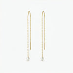 Gold chain earrings with pearl drops on a white background