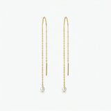Gold chain earrings with pearl drops on a white background