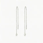 Pair of pearl drop earrings on thin chains against a white background
