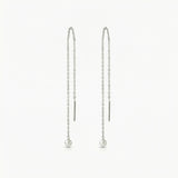 Pair of pearl drop earrings on thin chains against a white background