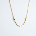 Gold necklace with small beads on a light gray background