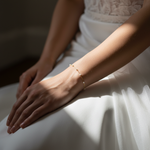 Close-up of a person's wrist wearing a delicate gold chain with small pearl bracelet with a soft focus background.