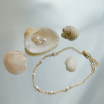 Gold bracelet with pearls and seashells on a light background