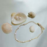 Gold bracelet with pearls and seashells on a light background