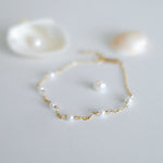 Gold bracelet with pearls on a light gray background